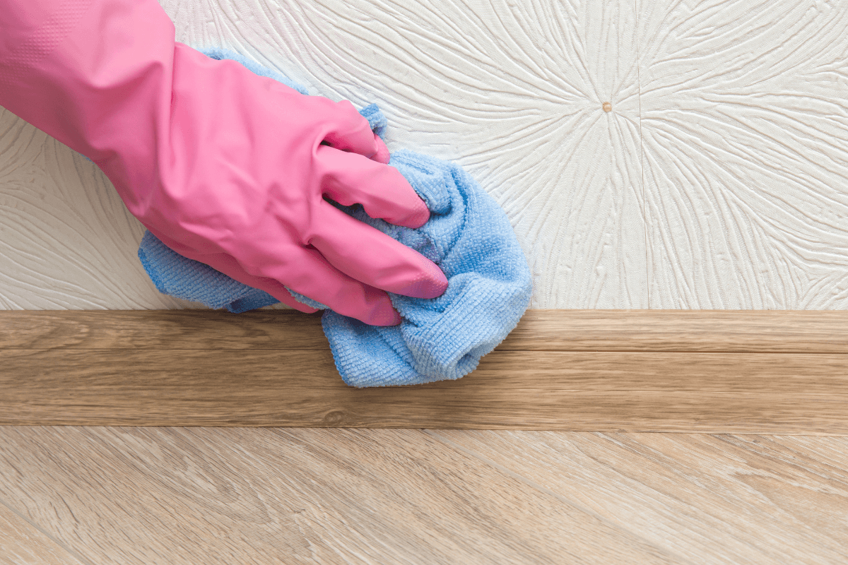 a hand in a pink glove wiping a surface with a blue cloth