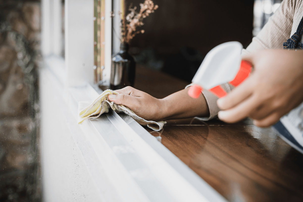 a hand holding a rag and cleaning a window