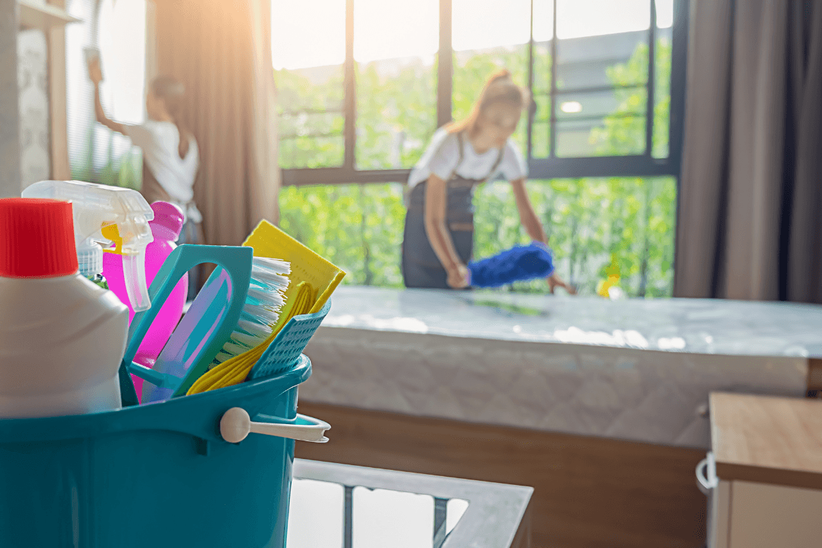 a bucket of cleaning supplies and a woman in the background