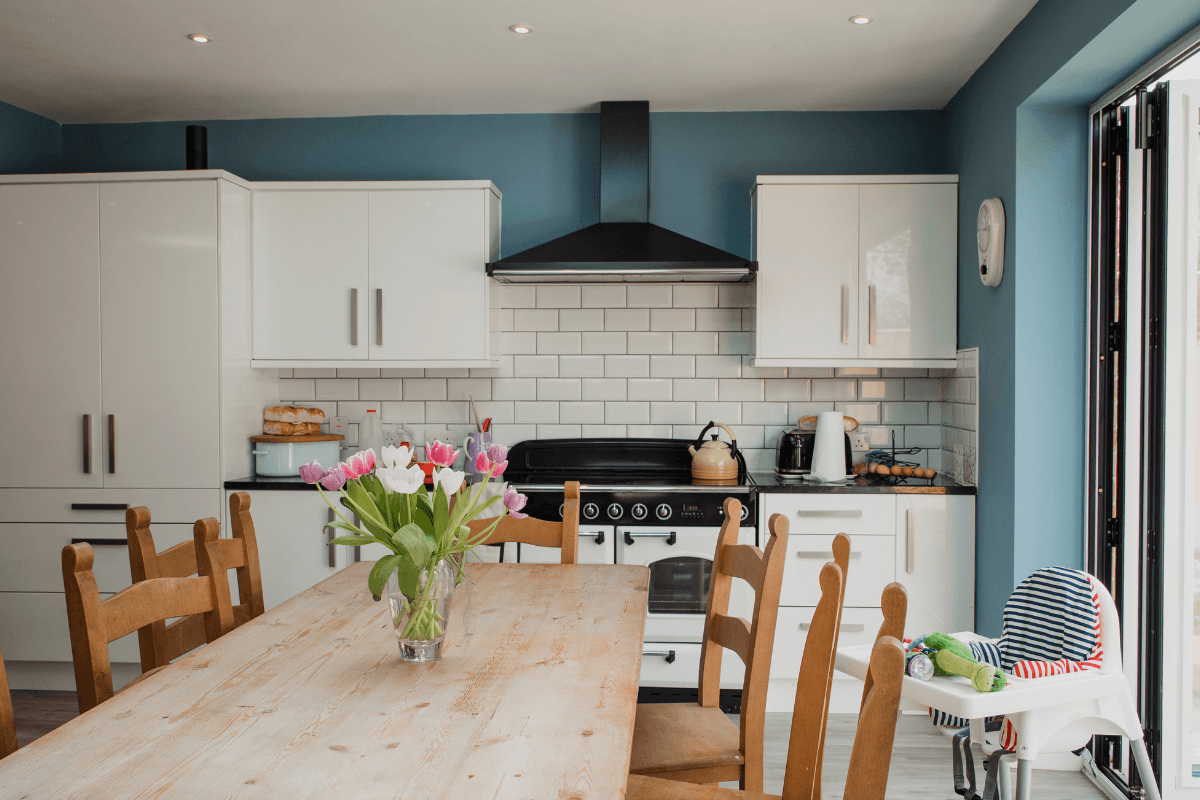 a kitchen with white cabinets and a table with flowers
