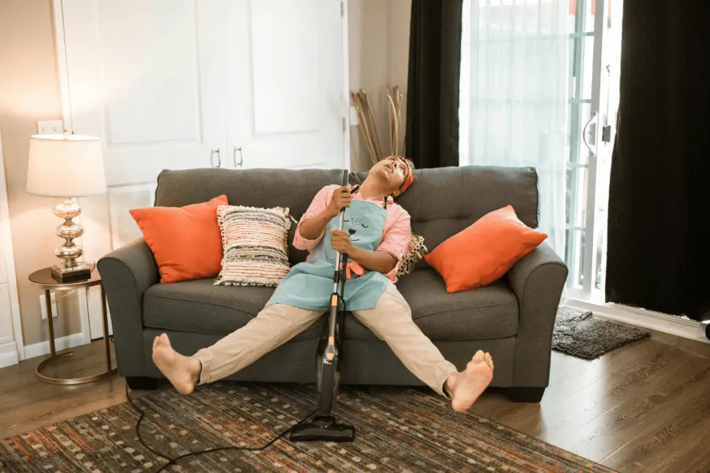 a person sitting on a couch with a vacuum cleaner