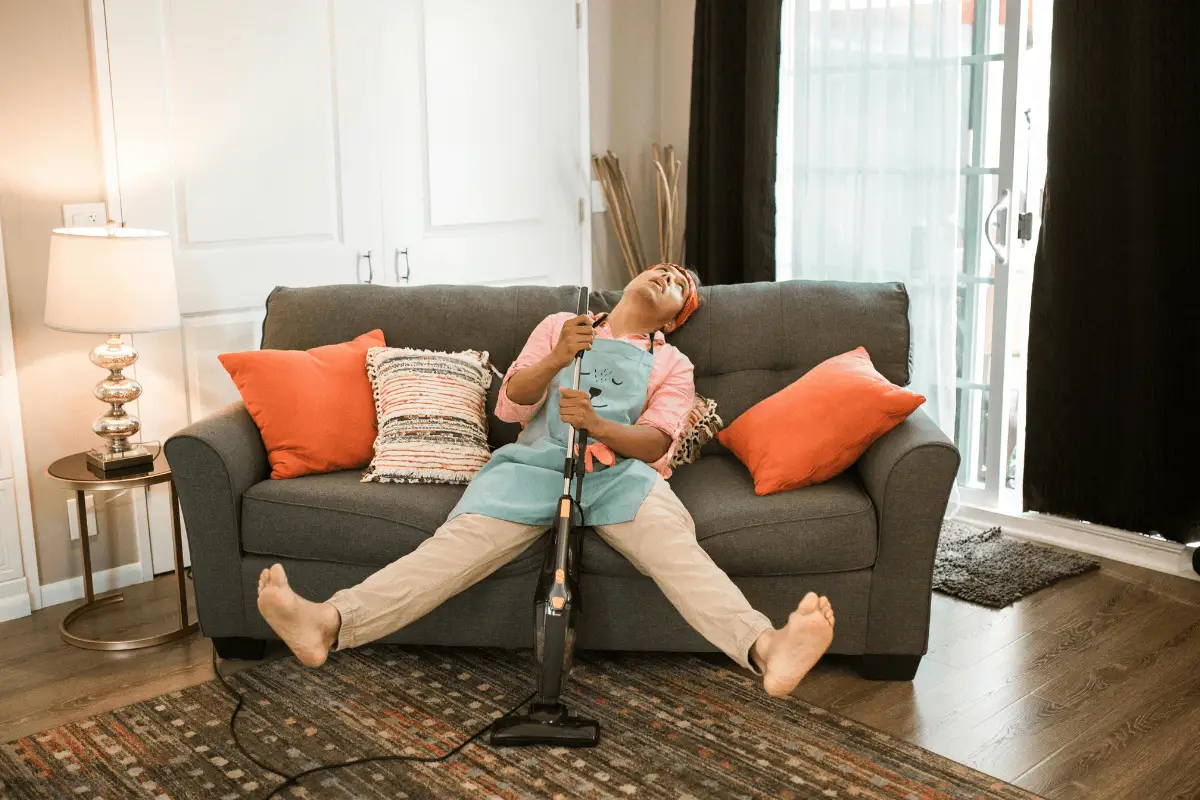 a person sitting on a couch with a vacuum cleaner
