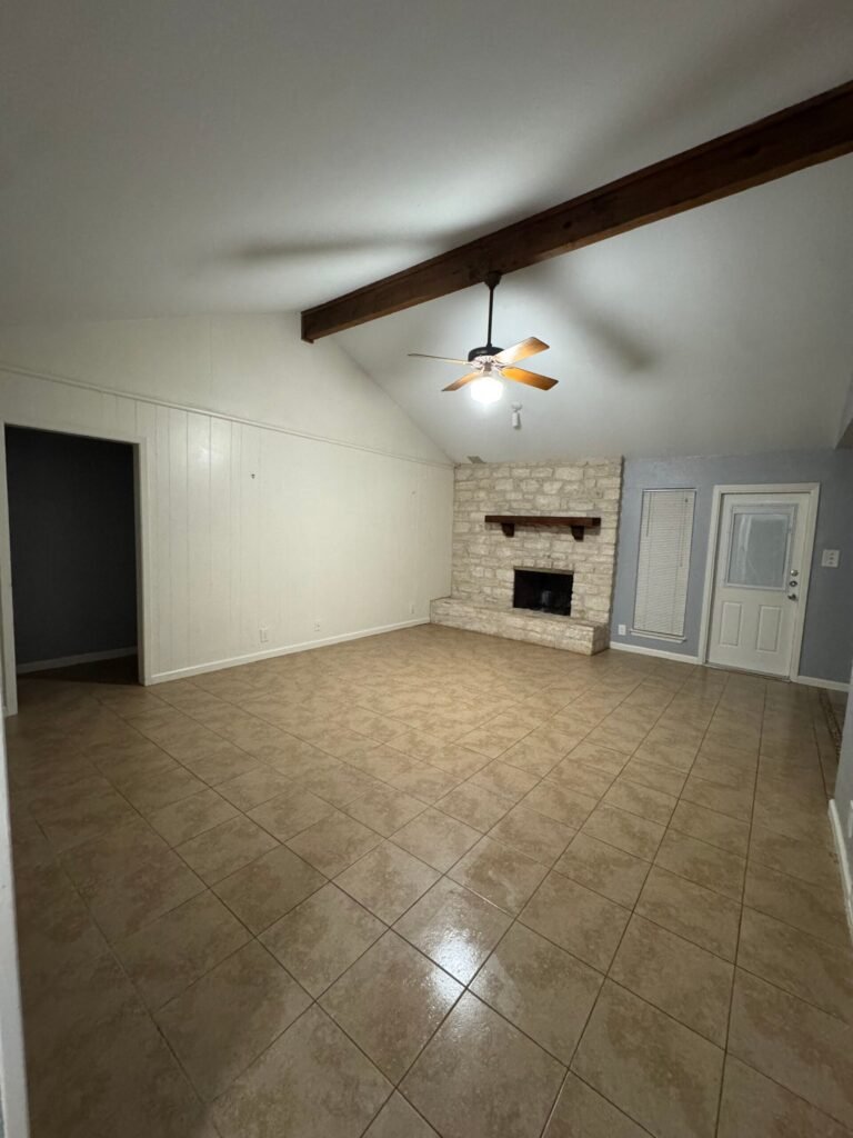 Empty living room with fireplace and shiny tile floor after a move-out cleaning